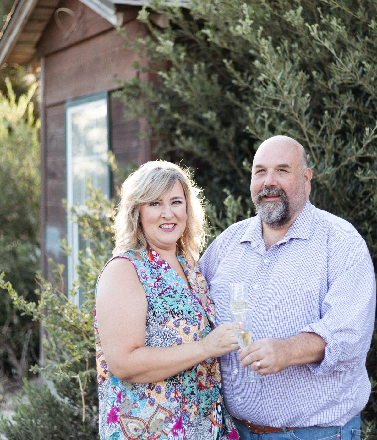 Blair and Laura Lott, founders of Rescue Dog Wines, holding glasses of wine among the vines